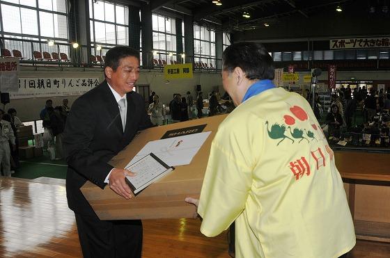 品評会で最優秀賞に輝いた菅井誠吾さんに賞状のほか、副賞として32型の液晶テレビが町長から贈られる様子の写真