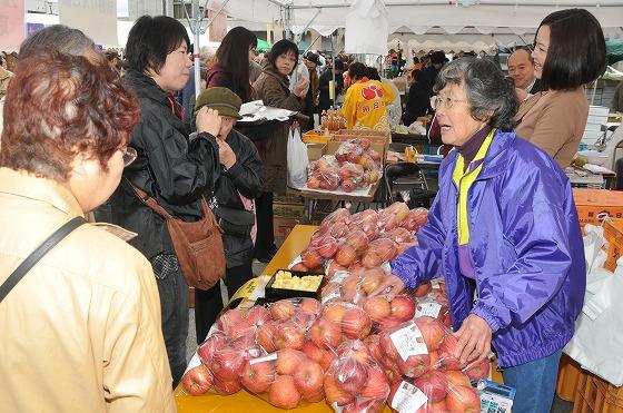 袋入りりんごを買い求める様子の写真