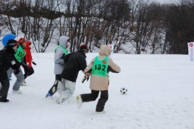 雪上サッカーでボールを追いかけるウサヒとプレーヤーの写真