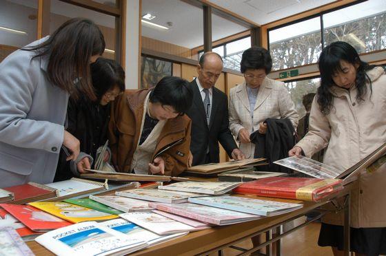 思い出の写真を目にしている歴代の卒業生や教師の写真