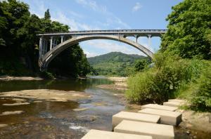 最上川の川岸からフットパスと明鏡橋を写した写真