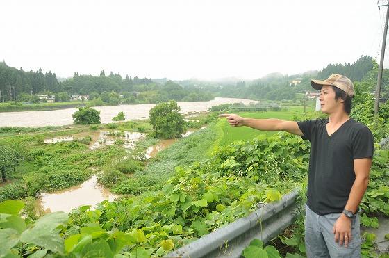 農地の所有者が川の様子を見つめる様子の写真