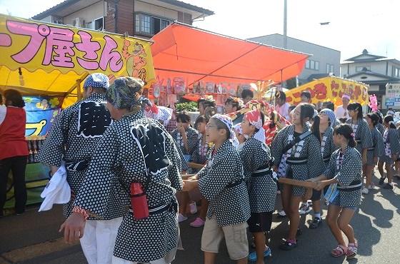 屋台の前を行く子ども神輿の様子の写真