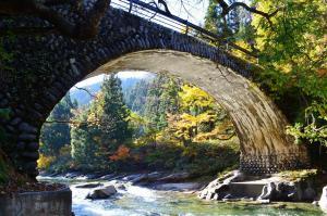 紅葉する木々とともに立木集落側から玉石橋を撮影した写真