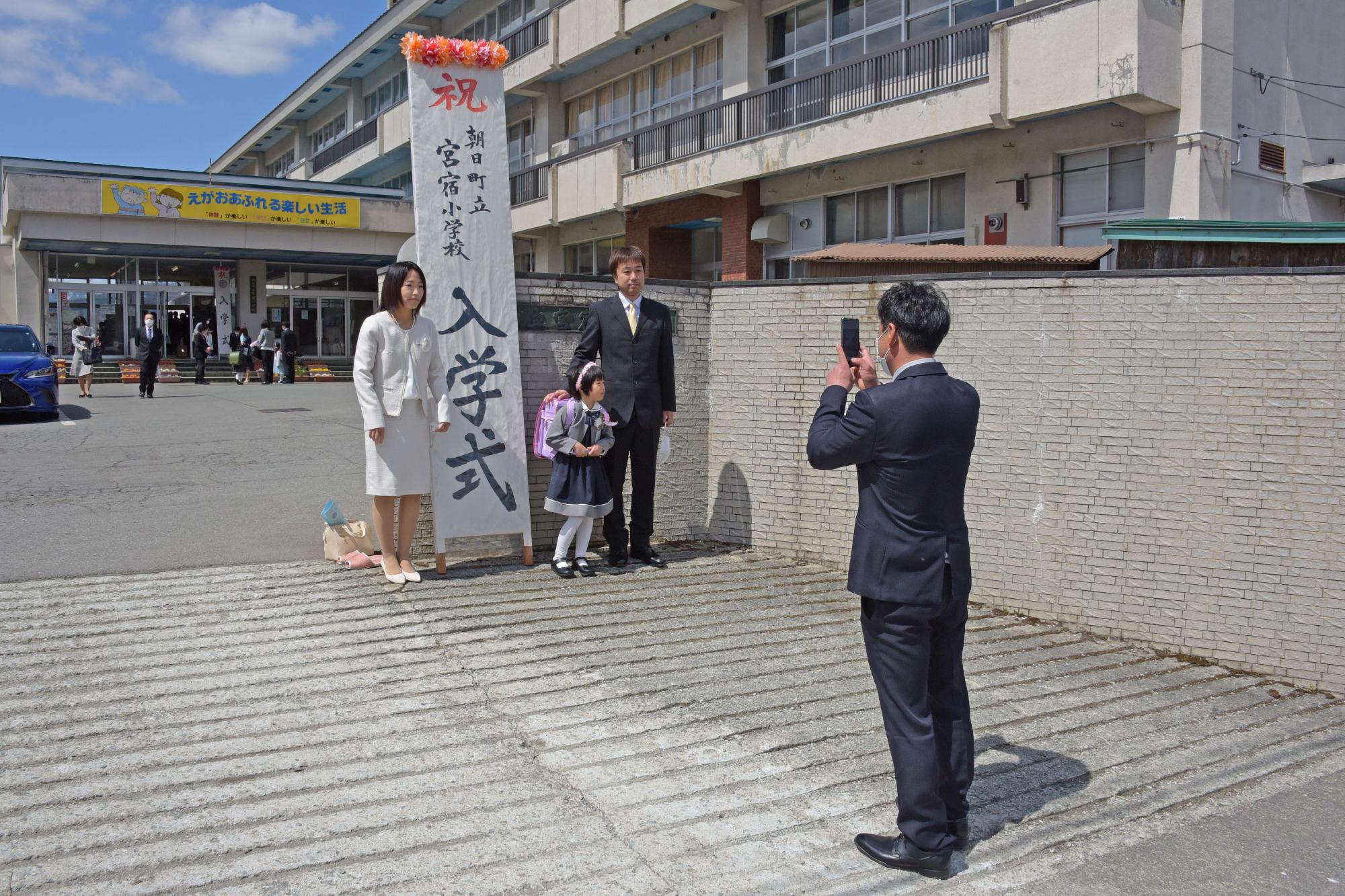 校門の前で記念写真を撮る新入生親子