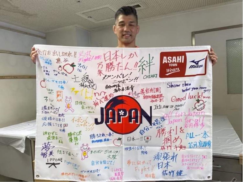 ミズノ株式会社を通じて、朝日町から贈った応援メッセージフラッグを手にする井上康生氏