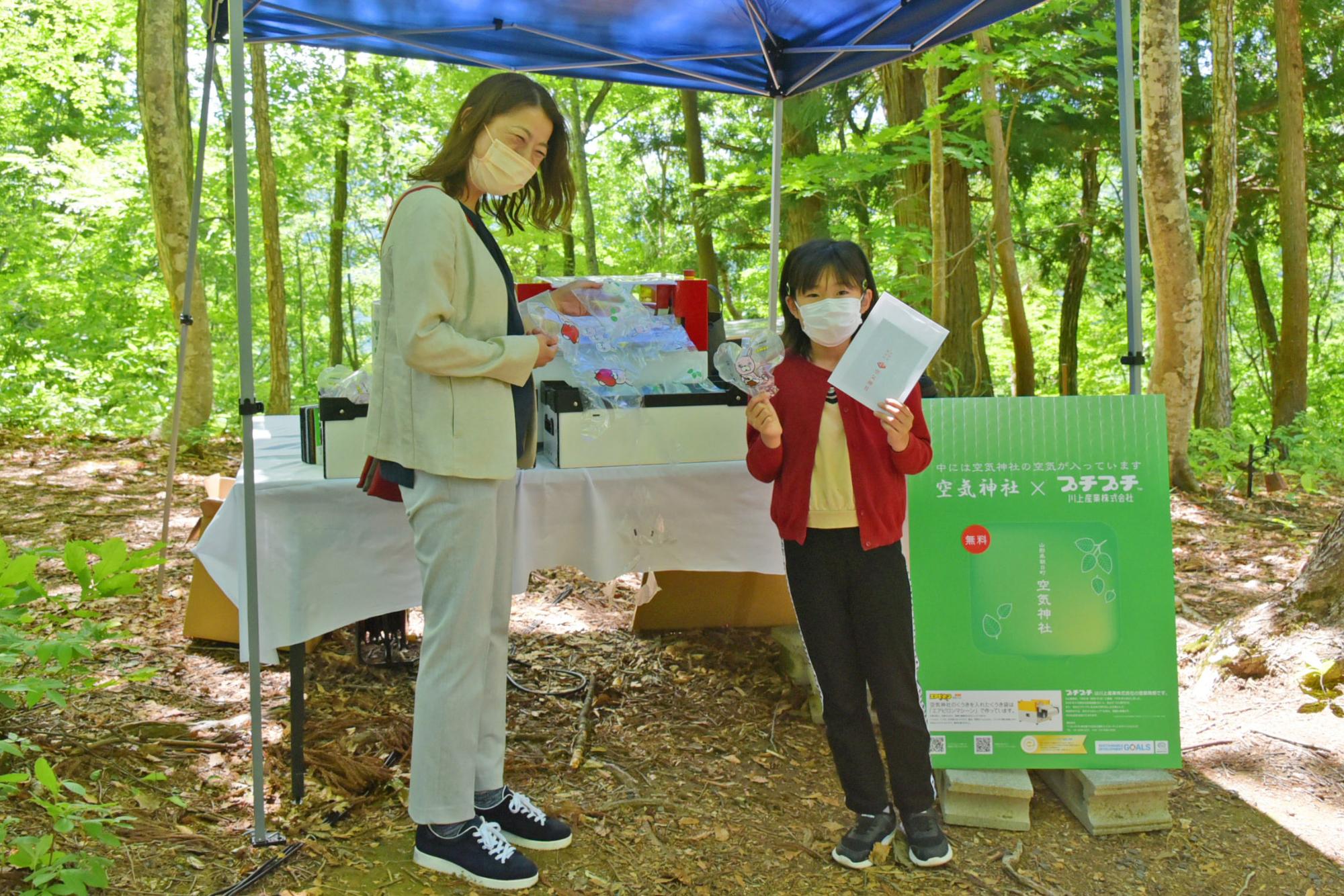 空気神社の空気が詰まったエアピロンをプレゼントする川上産業株式会社ブース