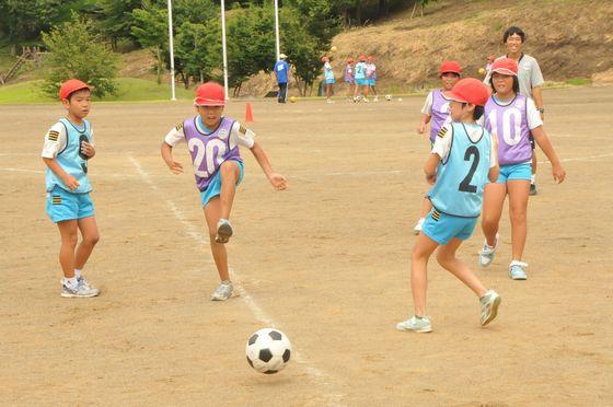 大谷小学校の校庭でミニゲーム中にシュートをする児童とそばにいる児童たちの写真