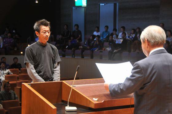 室内で25回出場の志藤正利さんが表彰を受けている写真