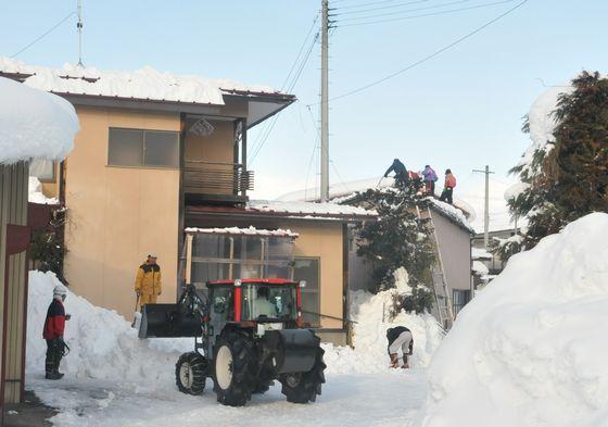 雪下ろし作業で地上にたまった雪を集めている様子の写真2