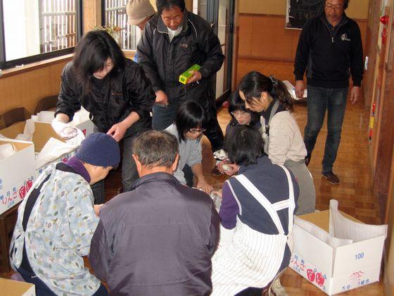 りんごの段ボール箱に入れて支援物資を運ぶ様子の写真