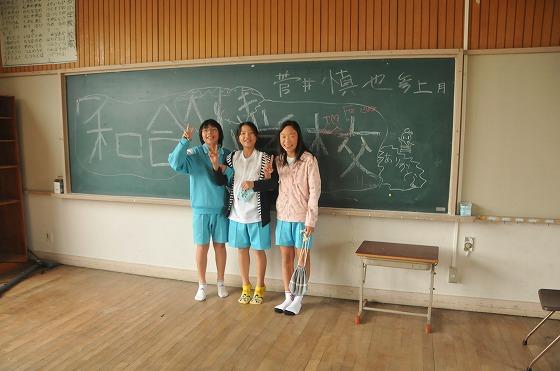 黒板の前で笑顔でピースして記念撮影する女の子たちの写真