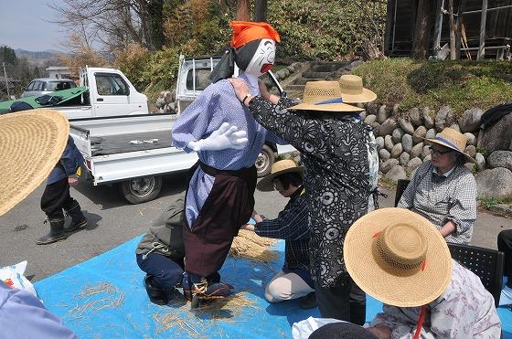 着物ともんぺを着せたかかしに足をつける様子の写真