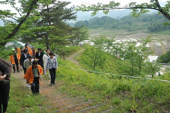 眼下の棚田を背景に、棚田とその保全活動の概要を説明している様子の写真