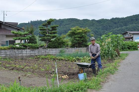 畑の中に立つ舟渡地区の五十嵐安男さんの写真