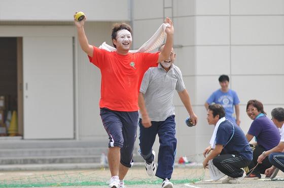 かぼちゃと白いタオルを持ちながら両手を掲げゴールしたオレンジ色のTシャツを着た白い粉まみれの顔の男性の写真