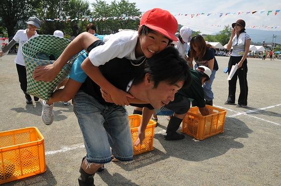 競技「親子でかぼちゃりんご狩り」でかごを持った子どもを背負ってゴールを目指す父親の写真