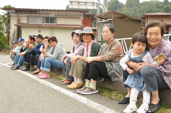 沿道で地域の住民が選手の到着を待っている写真