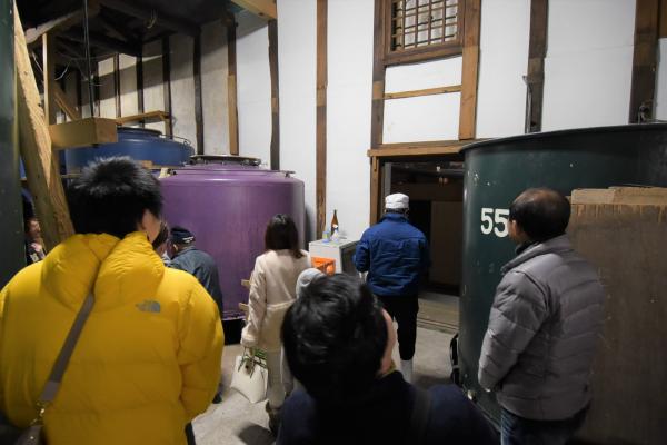 大きなタンクのある部屋を歩く多くの参加者の写真