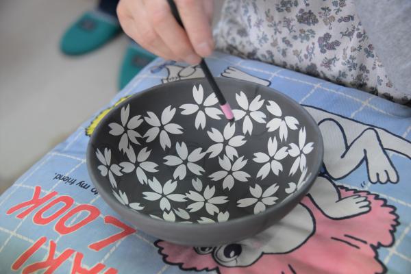 灰色の器に白く花びらの絵が描かれている写真