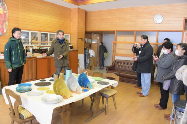 カラフルなお皿が展示されたテーブルと、その奥に立つ牧野さん