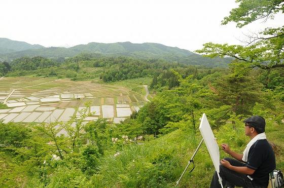 田園を前に絵を書く人の写真