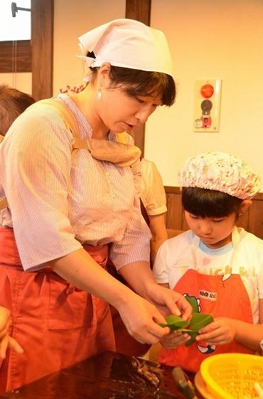 先生が児童に笹巻き作りを教えている様子の写真