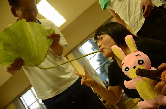 ハスの葉を使って酒を飲んでいる橋本さんの写真