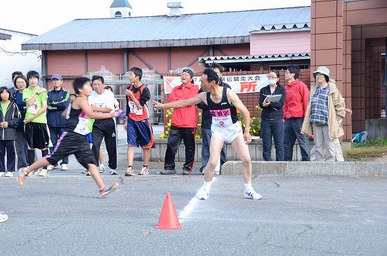 朝日町ワイン前で選手たちがタスキリレーをしている写真