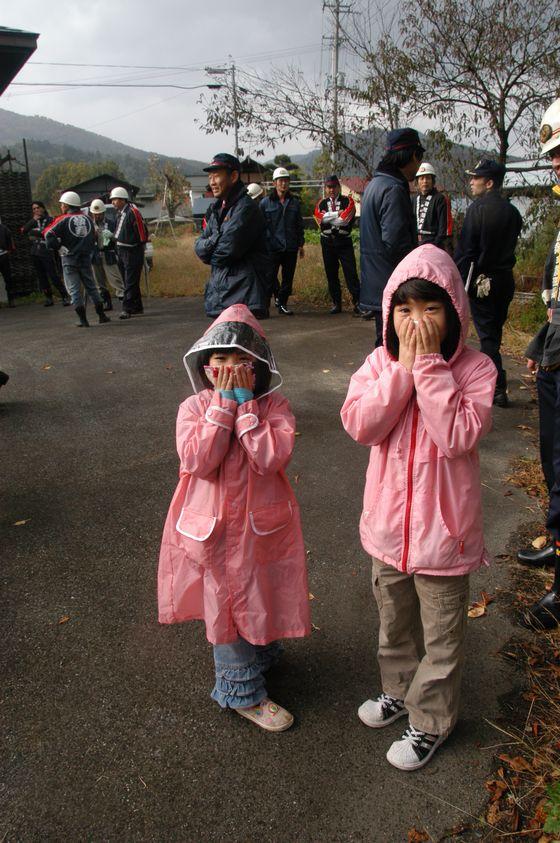 訓練の参加して煙がくさくて口を塞いでいる子供たちの写真
