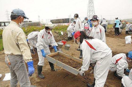 畑の土をふるいに掛ける作業を行う中学生ボランティアの写真