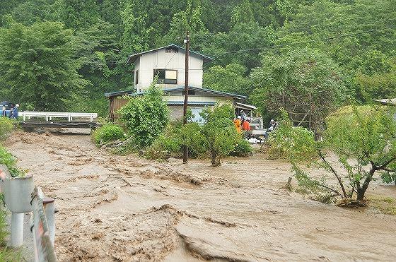 氾濫した濁流が民家と道を襲う写真