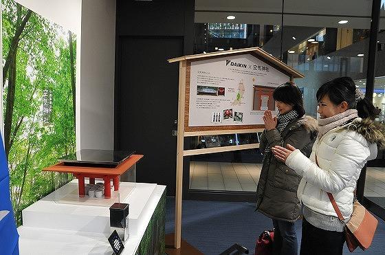 神社のミニチュアに手を合わせる来訪者の写真