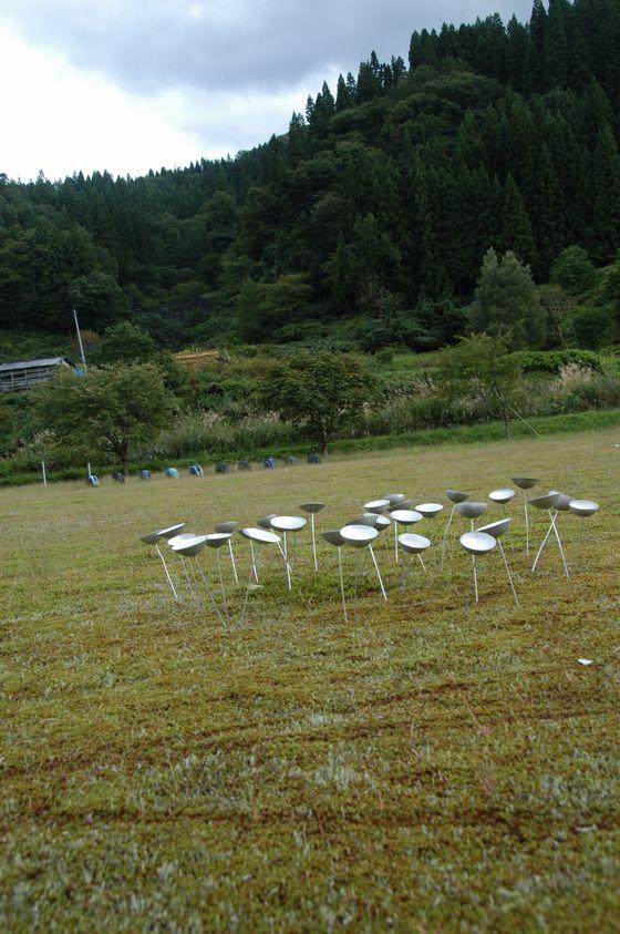 旧立木小学校の外に展示されている白い棒の上に大きな白い皿のようなものが載っている触ると音のなるオブジェの写真
