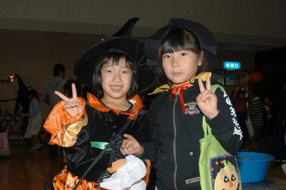 仮装してお菓子をもらいピースをして記念撮影する女の子の写真