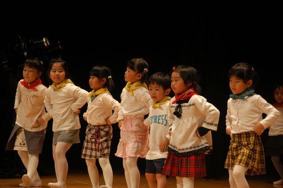 両脇腹に両手を当て踊る園児達の写真