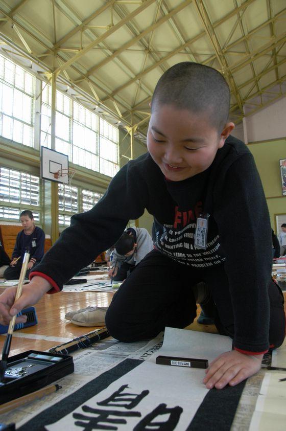 宮宿小書き初め大会で「晴れた空」を書こうとしている児童が筆に墨汁を付けている写真