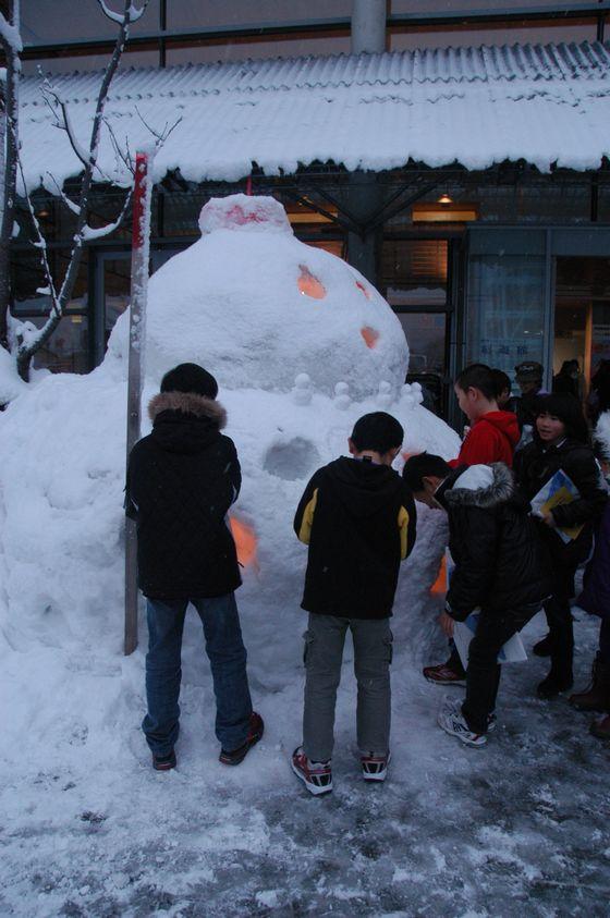 雪だるまとその周りに集まる子どもたちの写真