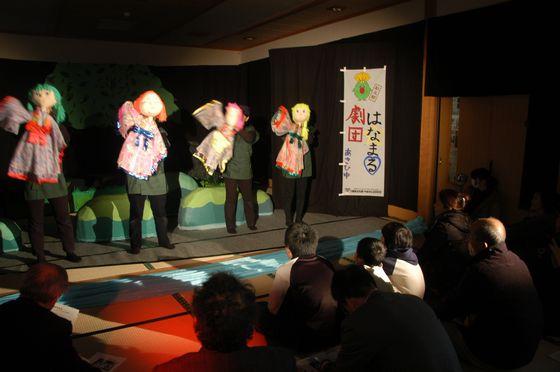 劇に見入っている地区民と子どもたちの写真