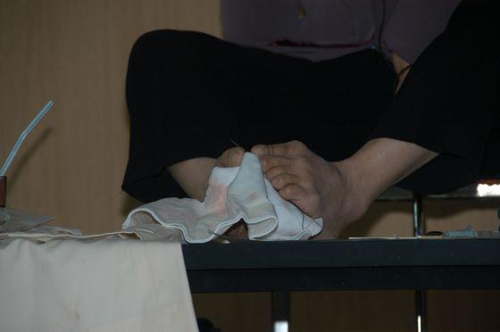 足で裁縫をする写真