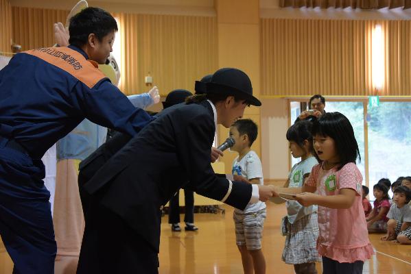 スケッチブックを子どもたちに渡す女性消防団員の写真