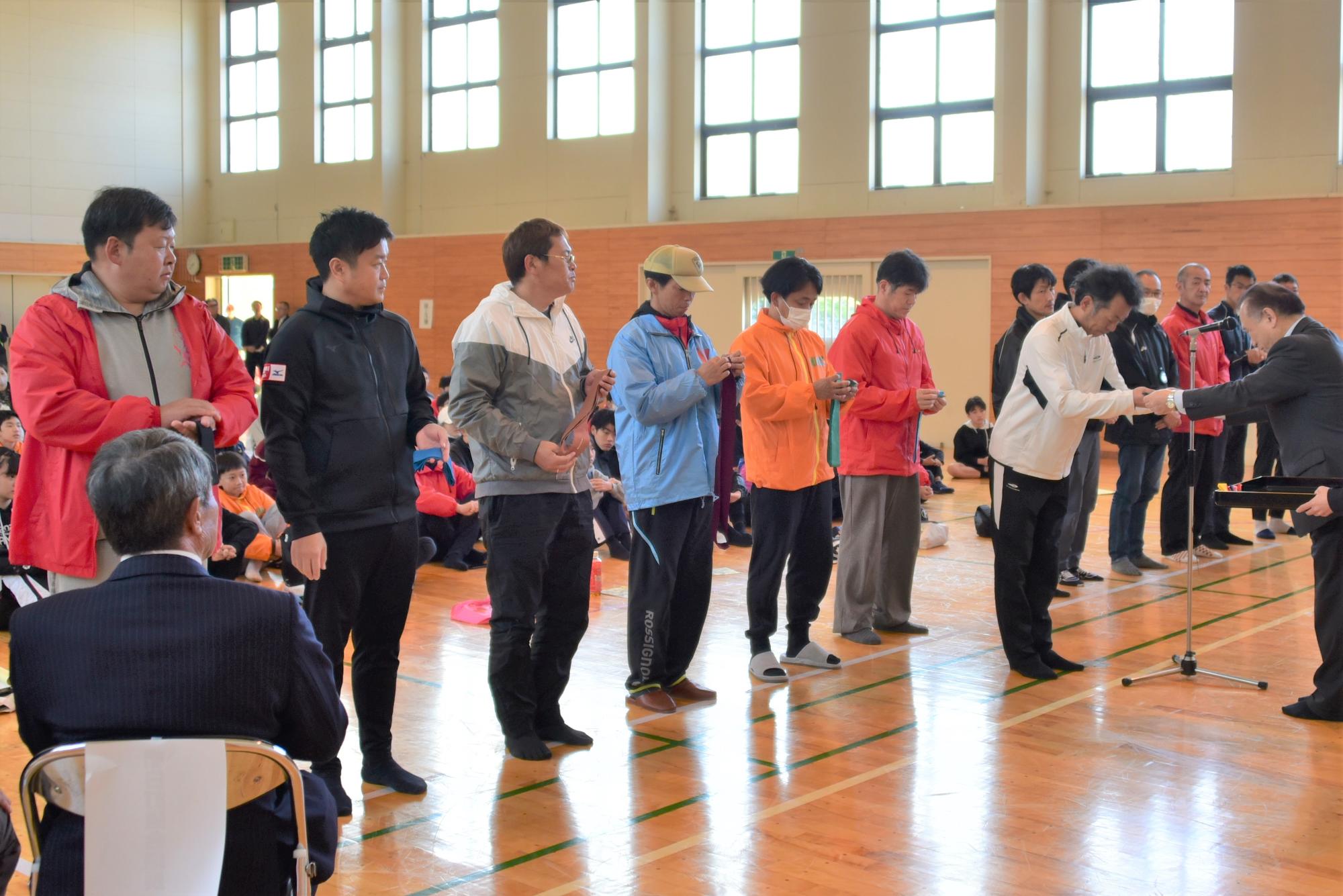 監督がタスキを受け取ります