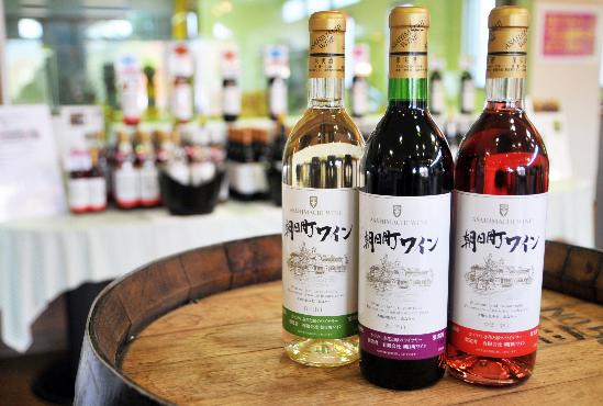 朝日町の種類豊富な3種のワインが樽の上に並んでいる写真