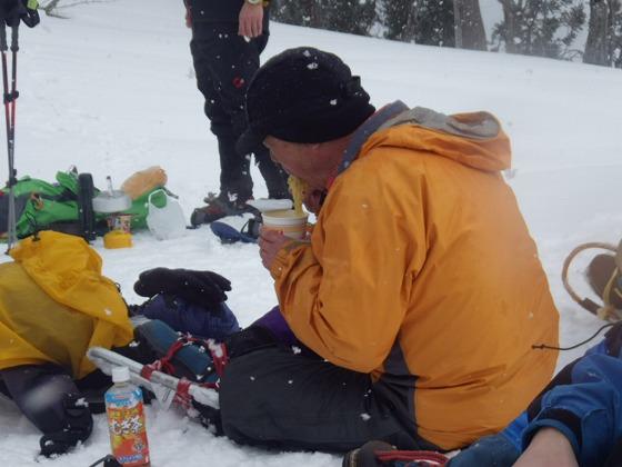 山でカップめんを食べている大人参加者の写真