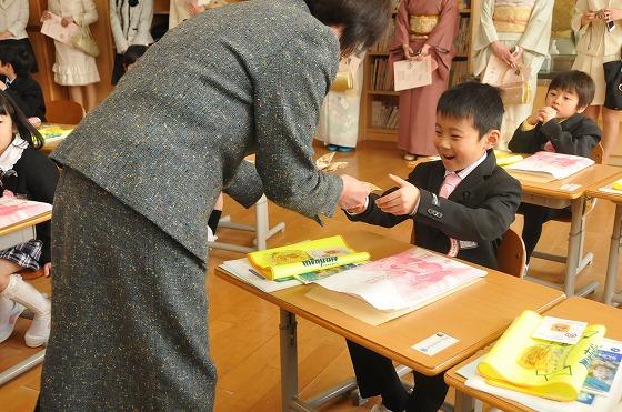袋を手渡す白田氏と受け取る新一年生の写真