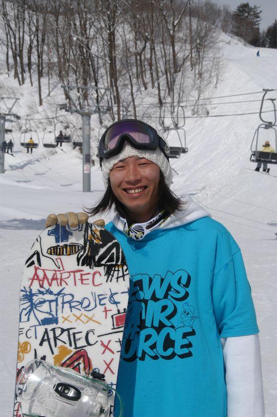 ゲレンデでスノーボードを手に笑顔の渡辺さんの写真