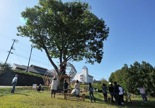 Asahi自然観敷地内にある栗の木に設置されたツリーハウスをみつめるイベント来訪者たちの写真