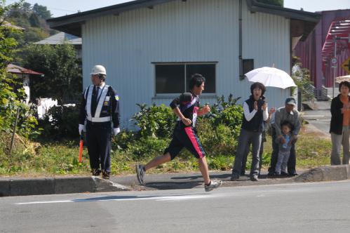 道で声援されて足を速める選手たちの写真