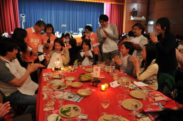 仲間の誕生日をサプライズでお祝いしていたところに、食改メンバーが祝福のワインを注ぐ様子の写真