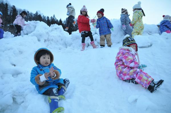 積まれた雪の上で遊んでいる子どもたちの写真